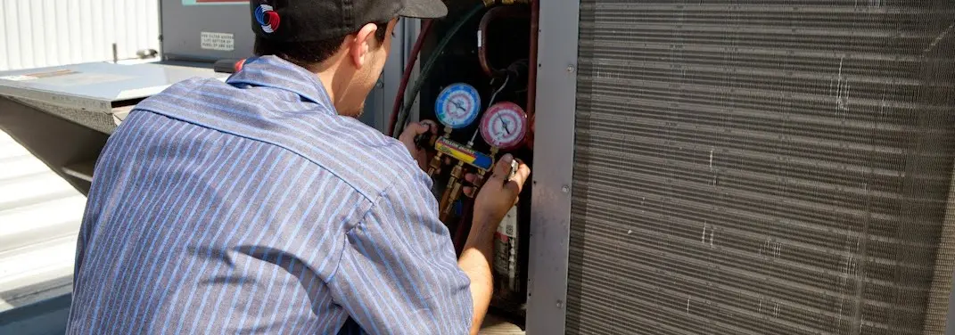 HVAC technician servicing a condenser unit in Portland